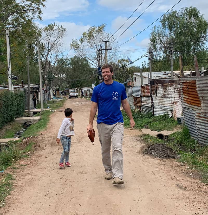Un jóven con remera azul y biblia en mano